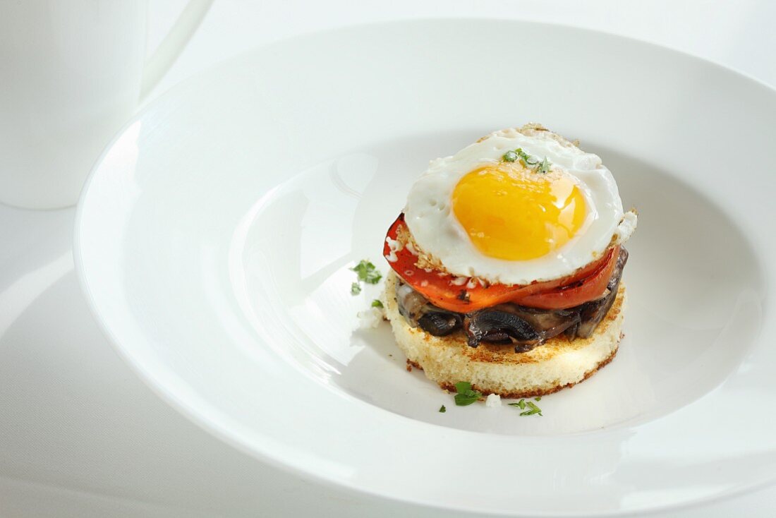 A toast canapé with mushrooms, tomato and fried egg
