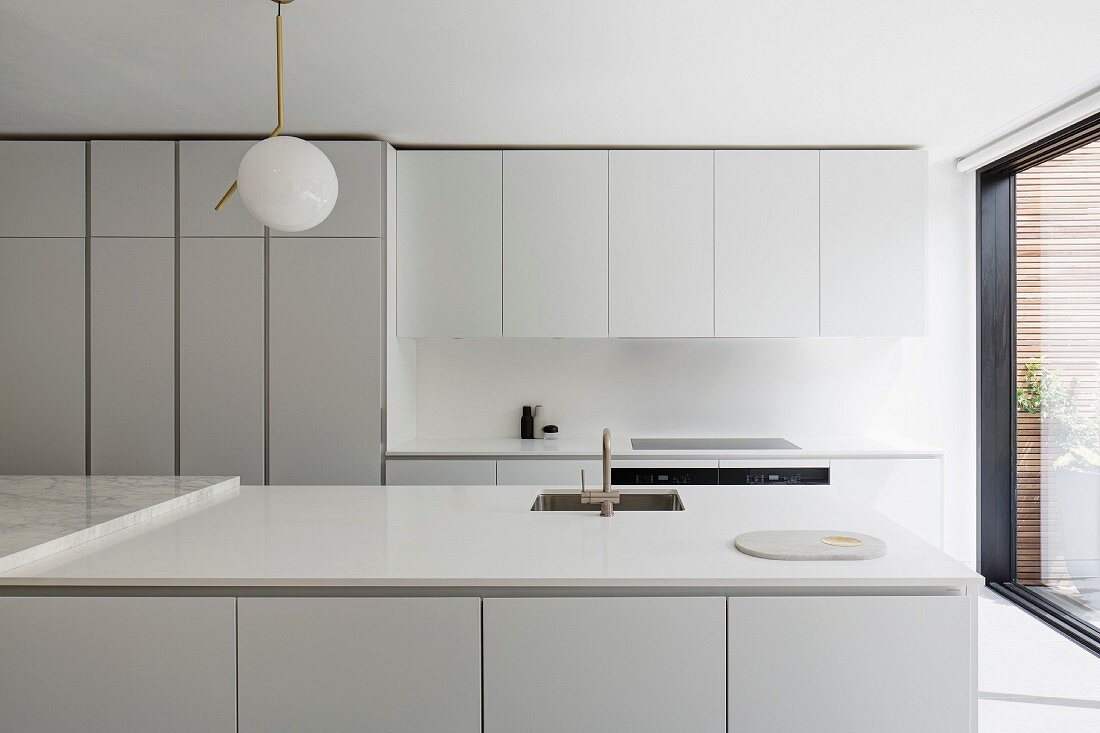 White, designer kitchen with wall units, tall cupboards and island counter