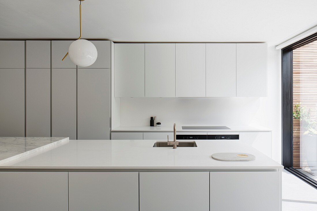 weiße Designerküche mit Hängeschränken, Hochschränken und Küchentheke