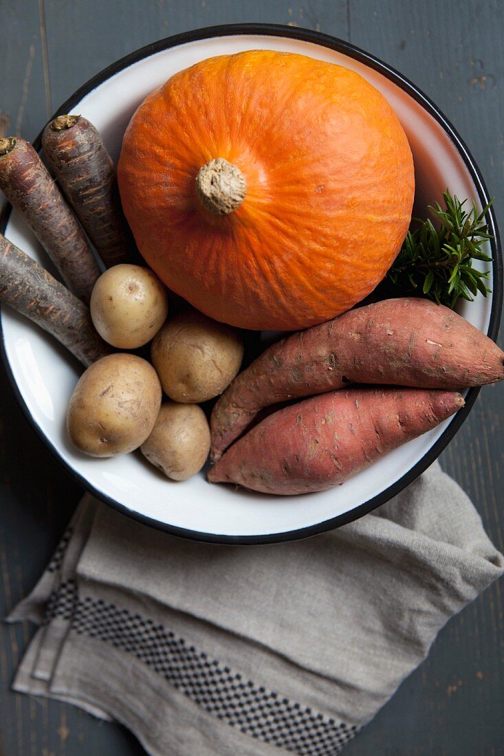 A pumpkin and root vegetables in a bowl