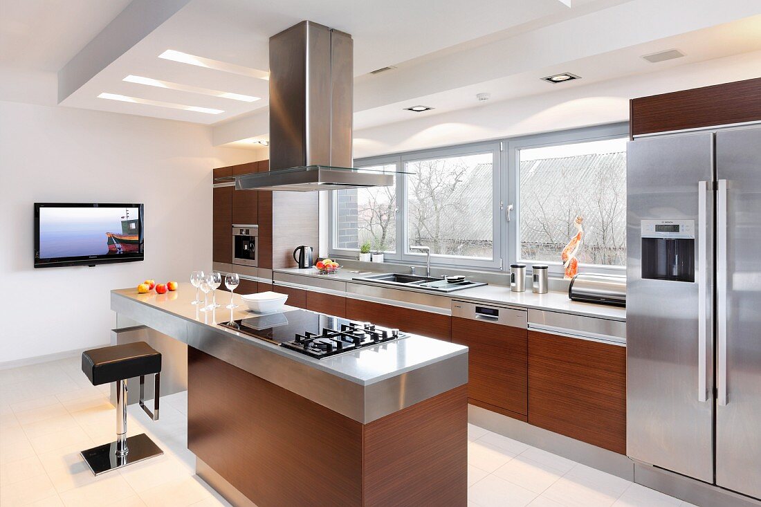 Luxury kitchen with exotic-wood fronts and stainless steel fitted appliances, island counter and plasma TV