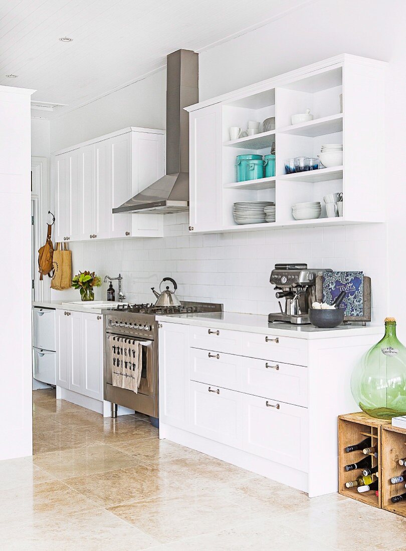 White country-style fitted kitchen with stainless steel gas hob and extractor hood