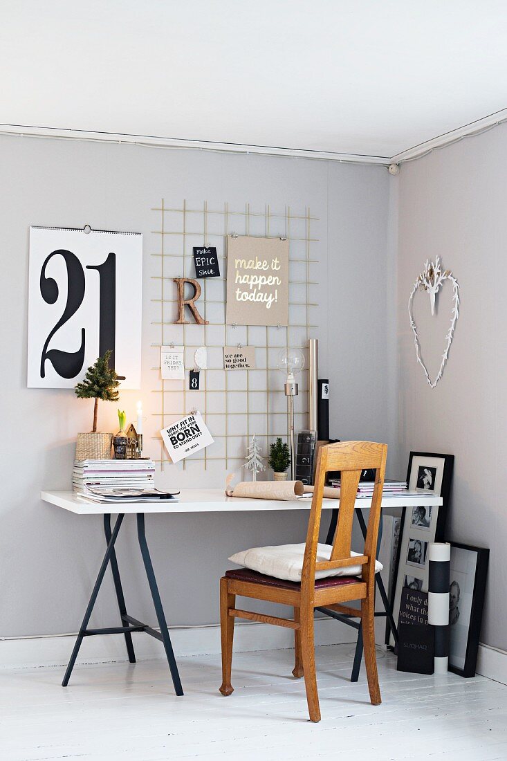 Schreibtisch vor grauer Wand mit einem Gitter als Memoboard