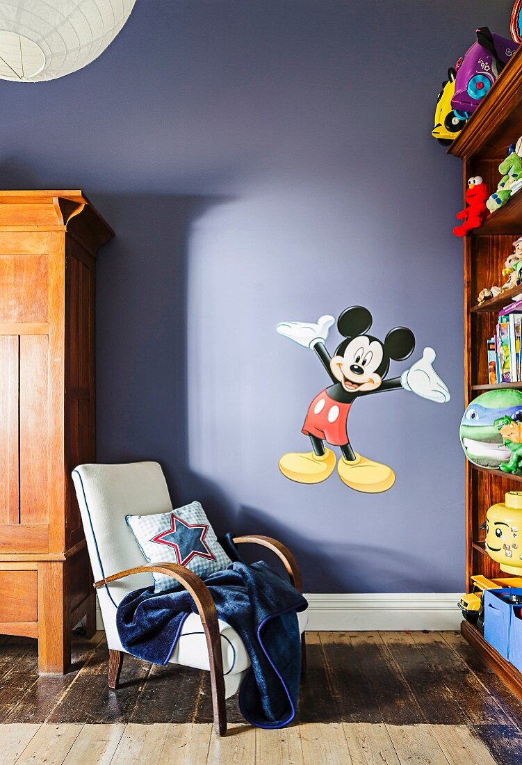 Retro-Sessel vor violetter Wand mit 'Mickey Mouse' Wandtattoo in Kinderzimmer