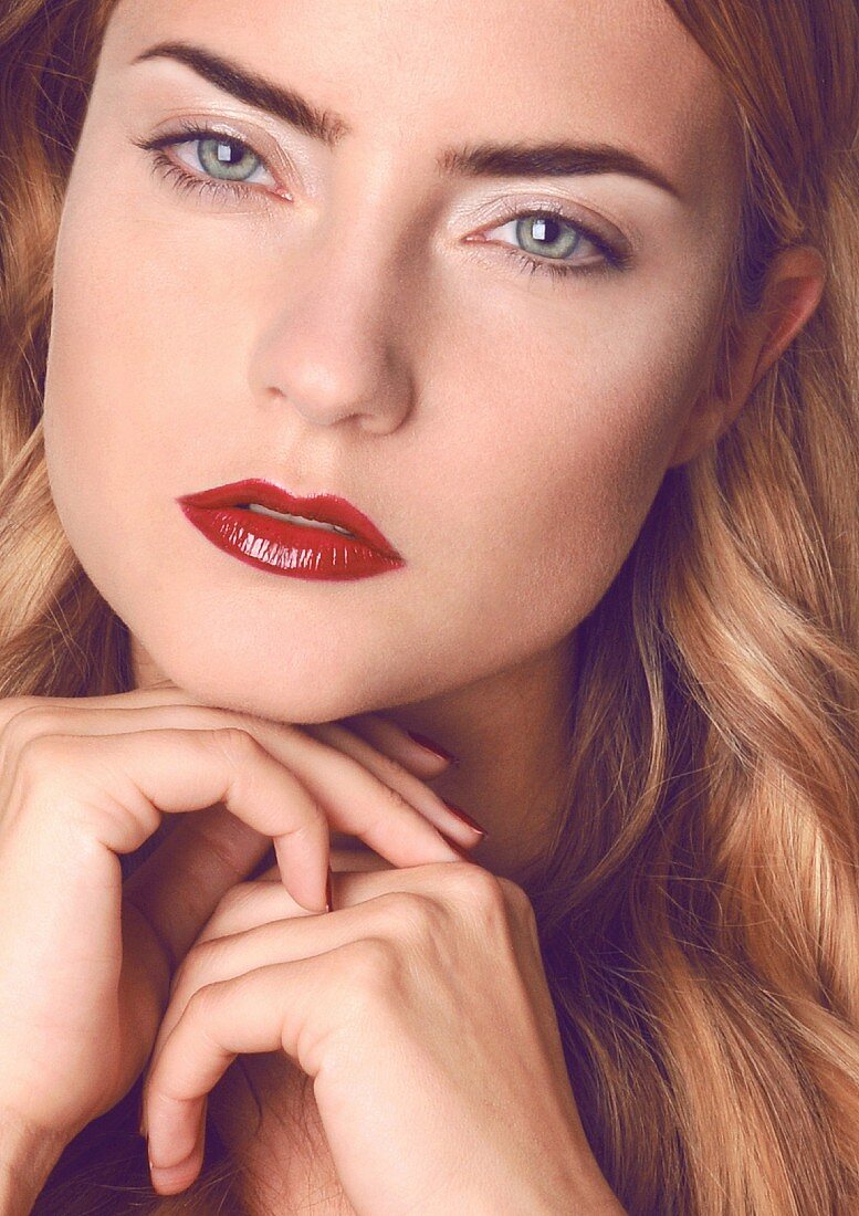 A dark blonde woman with blue eyes and red lipstick (close-up)