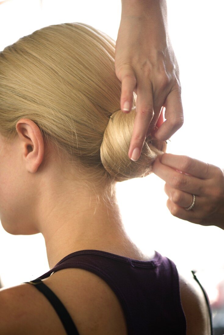 Haarknoten bei junger Frau wird mit Haarnadeln fixiert