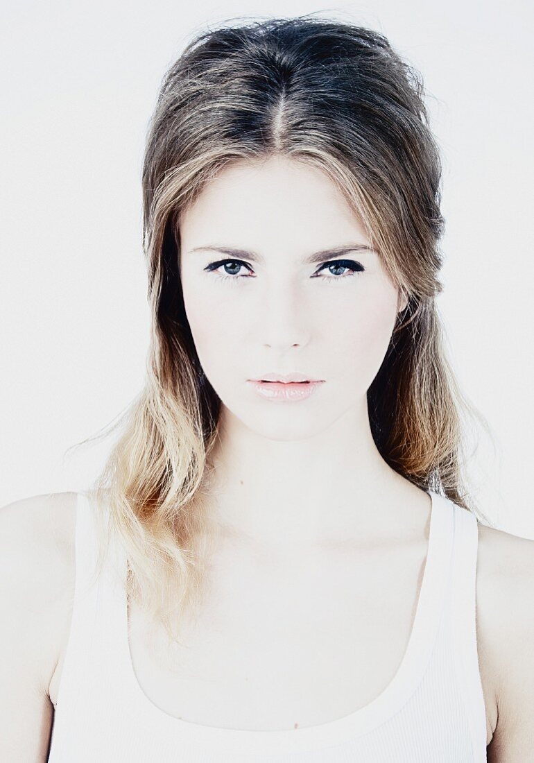 A young brunette woman wearing a white vest top