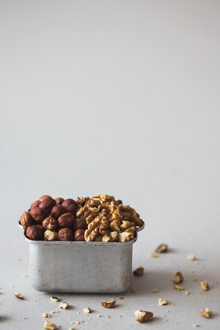Hazelnuts and walnuts in a metal container