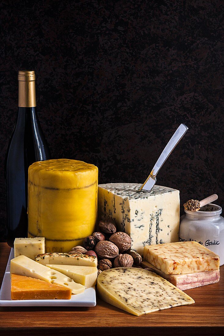 A cheese platter with mustard, walnuts and wine