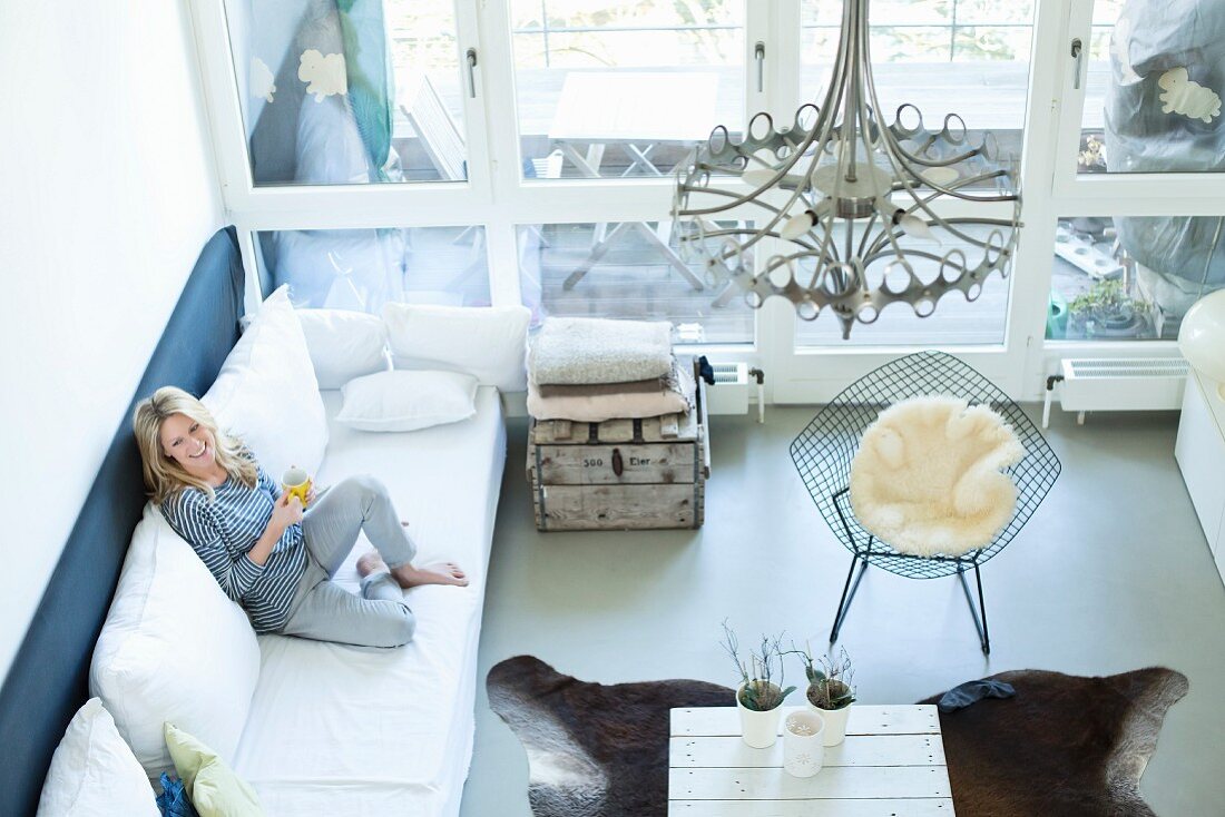 Frau relaxt auf Sofa in modernem Wohnzimmer (Blick von Oben)