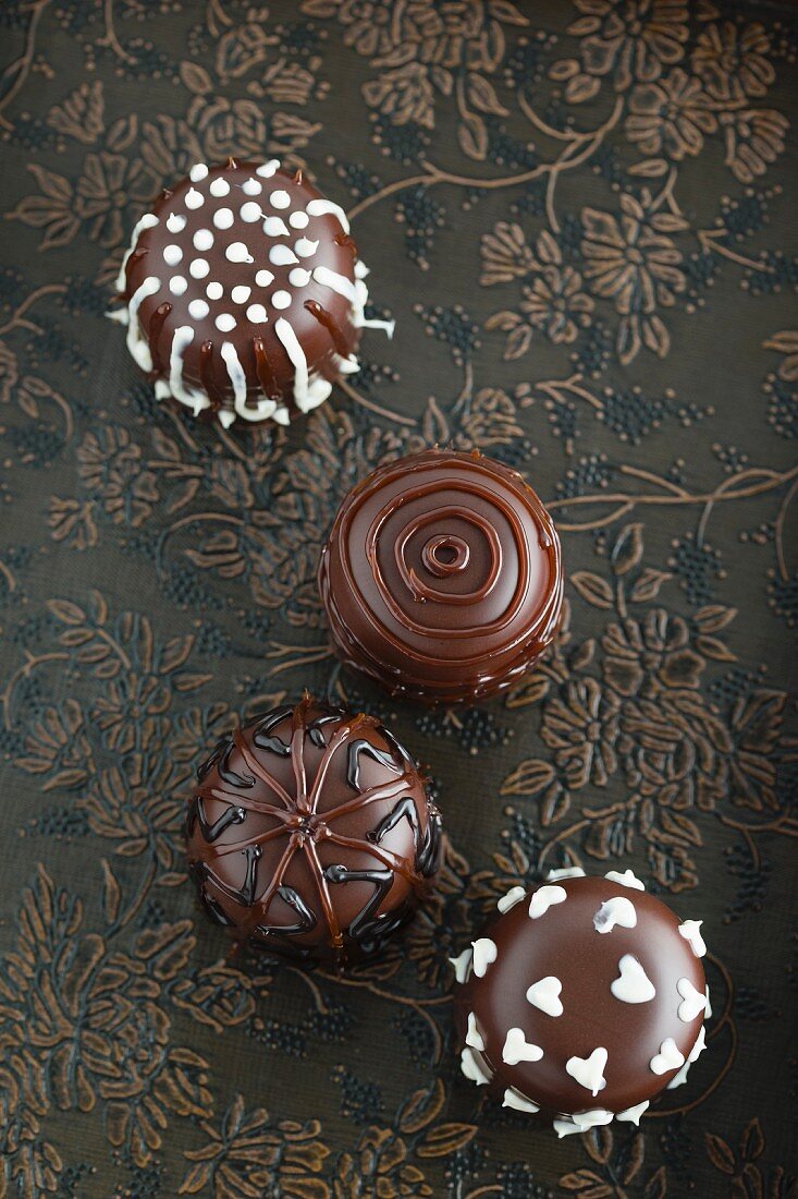 Four chocolate marshmallows decorated with icing (seen from above)