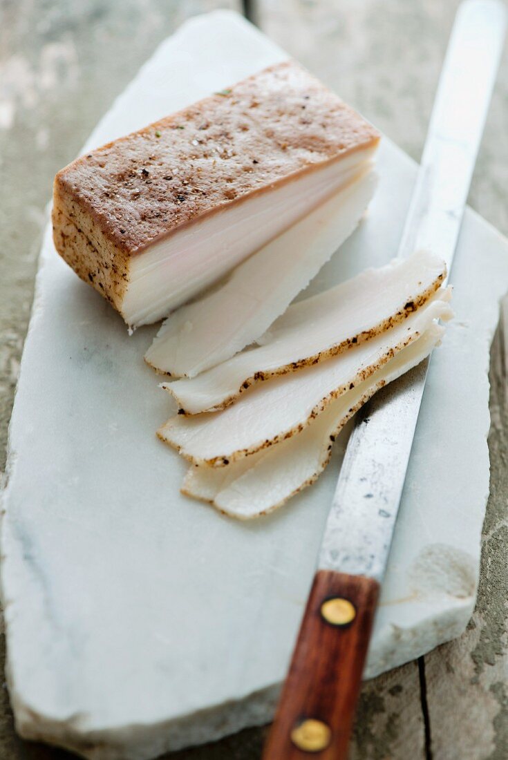 A slice of lardo di colonnata from Italy on a marble platter