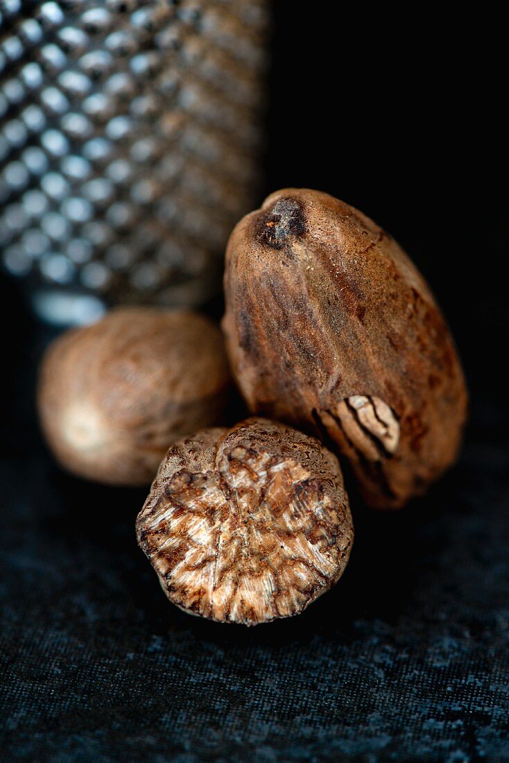 A close-up of whole and partially grated nutmegs