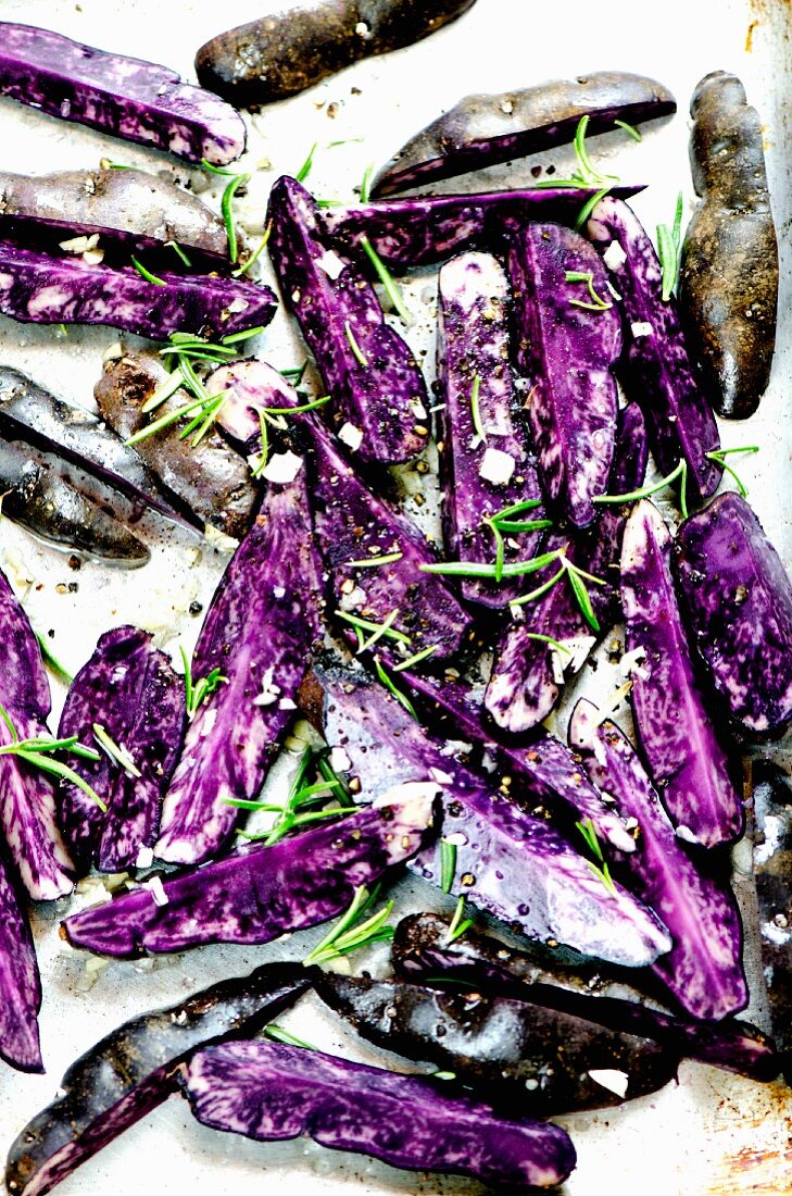 Violette Kartoffeln mit frischen Kräutern und Olivenöl auf dem Backblech