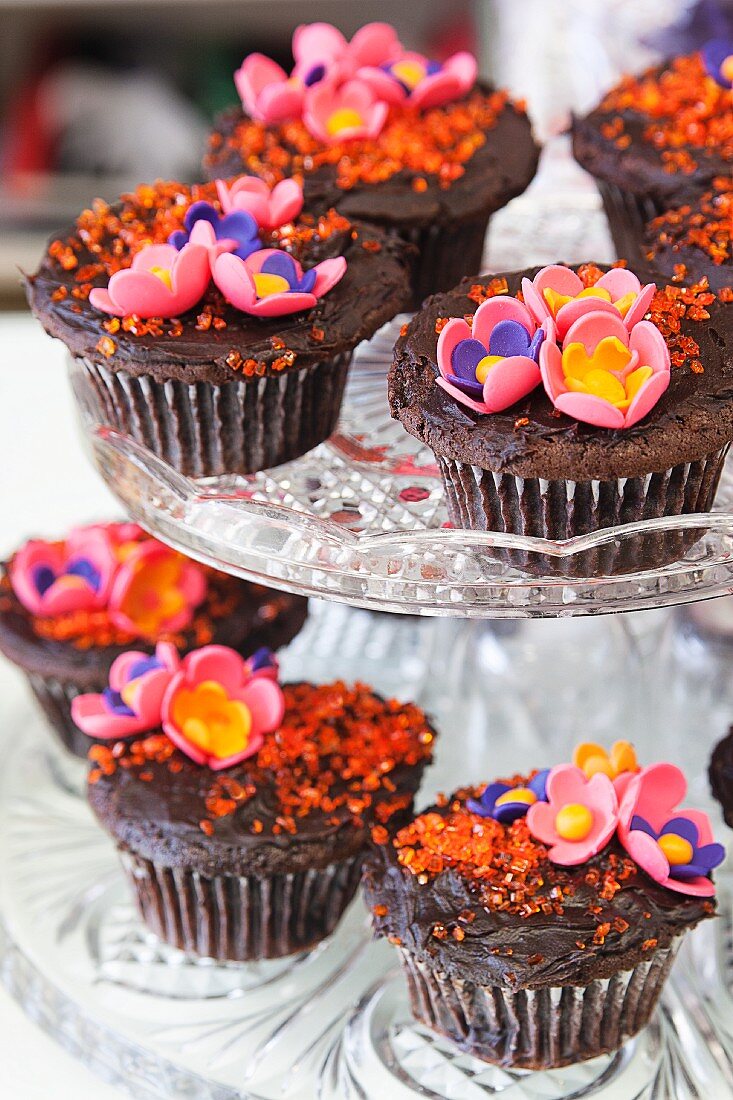 Schokoladencupcakes mit bunten Zuckerblumen auf Etagere