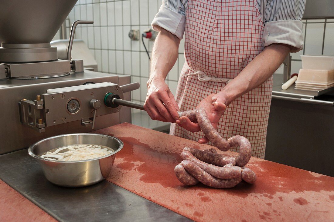 A butcher making sausages: intestines being filled