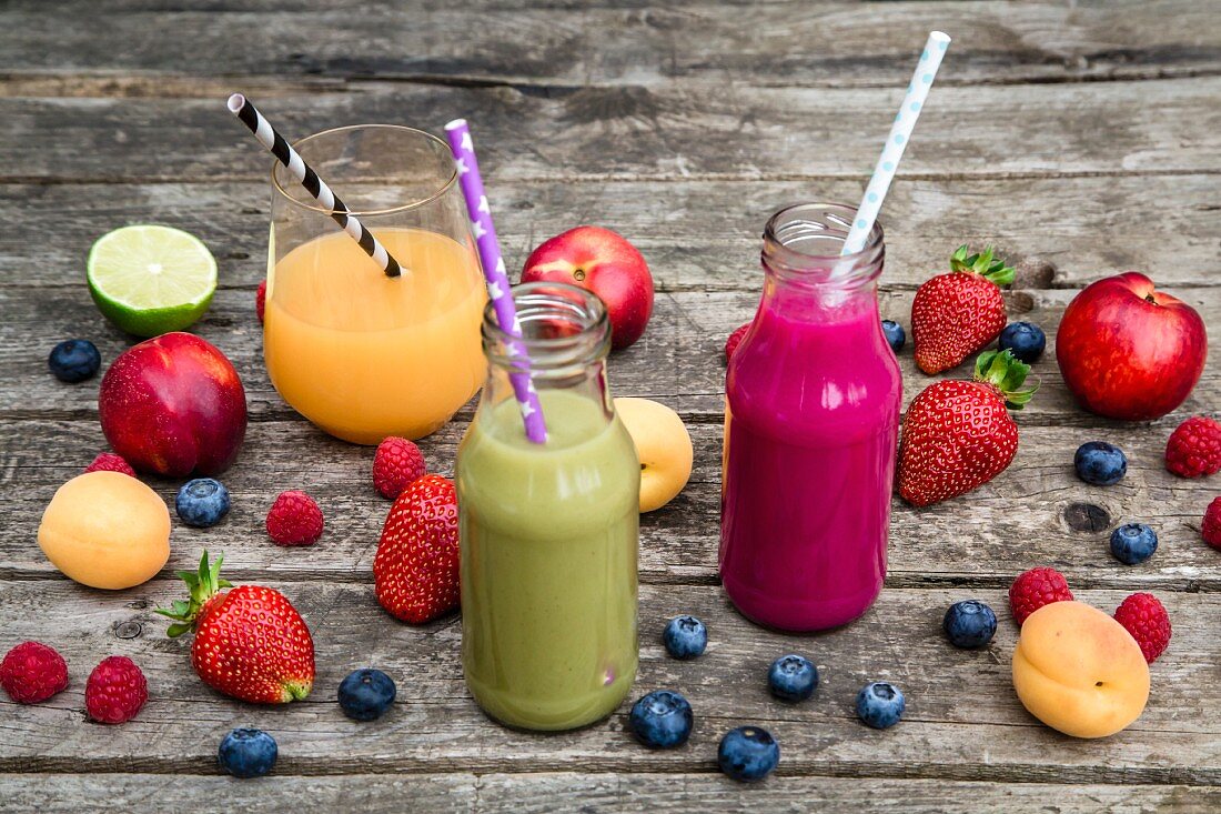 Three different fruit smoothies on a wooden table