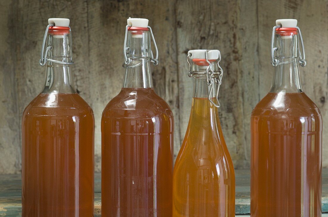 Bottle of apple juice with a flip-top jar on a rustic shelf