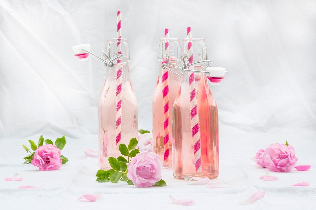 Bottles of homemade rose lemonade with straws