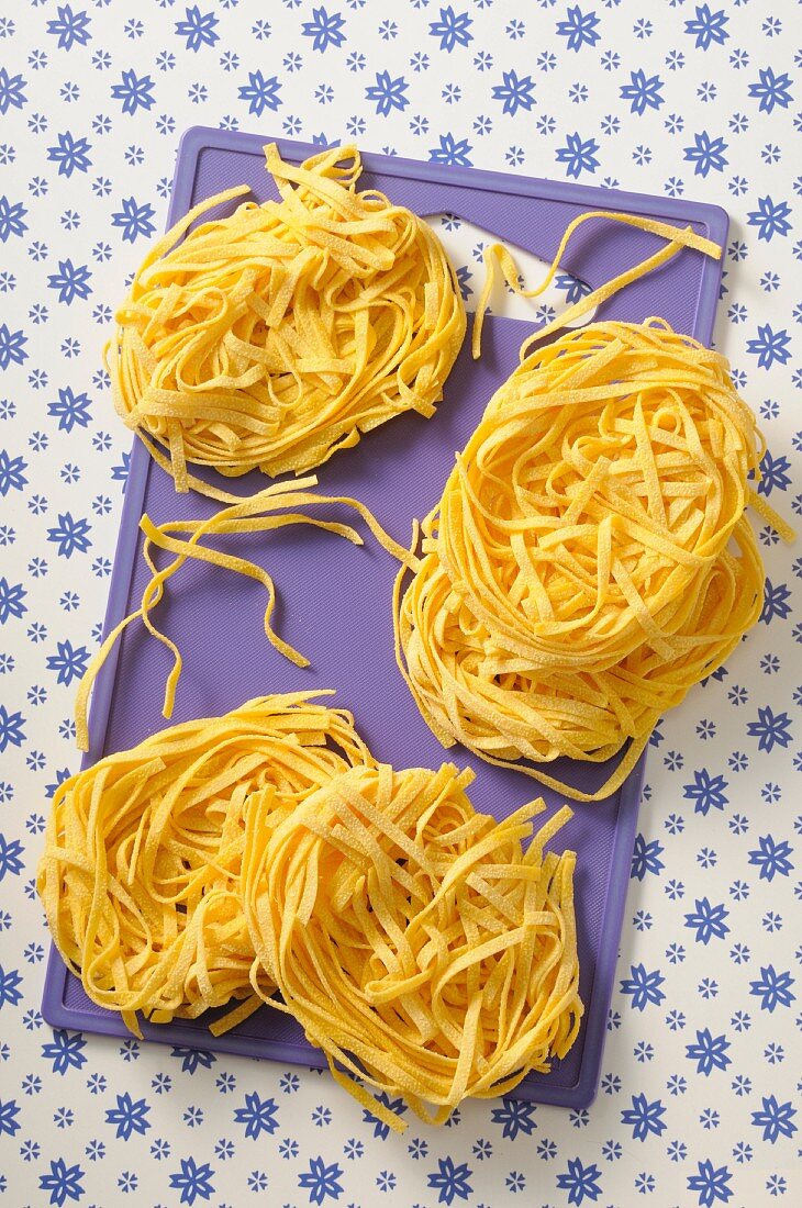 Homemade tagliatelle on a chopping board (seen from above)