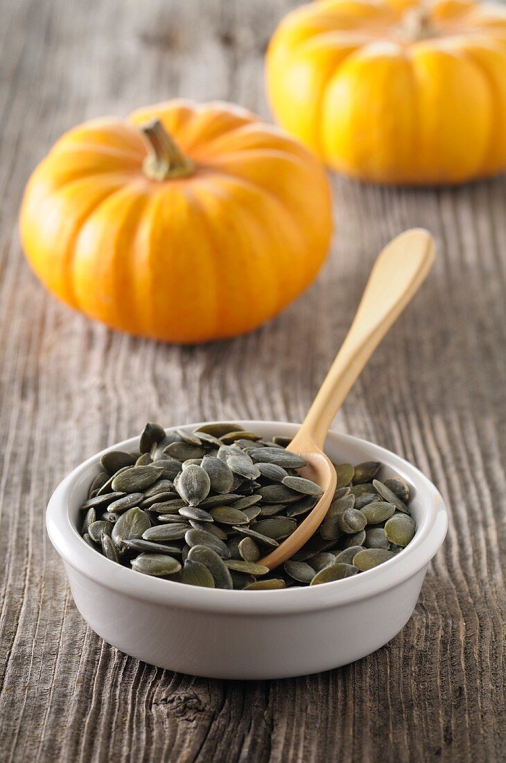 A dish of pumpkin seeds with a spoon