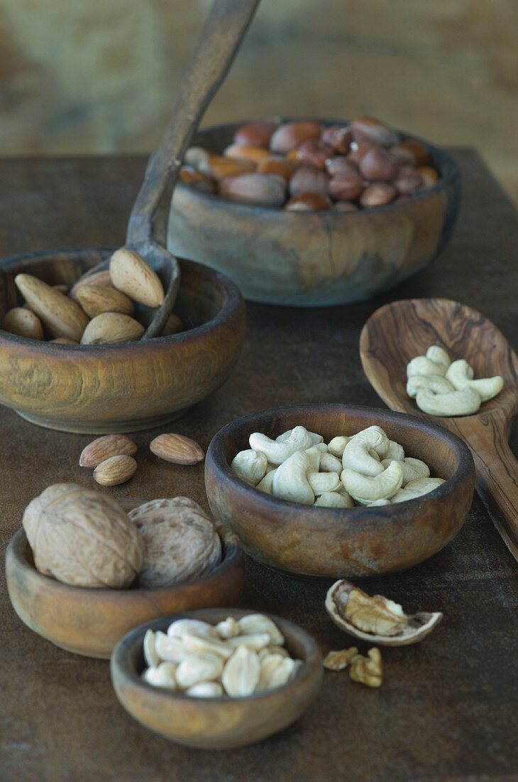 Various nuts with and without shells in wooden bowls