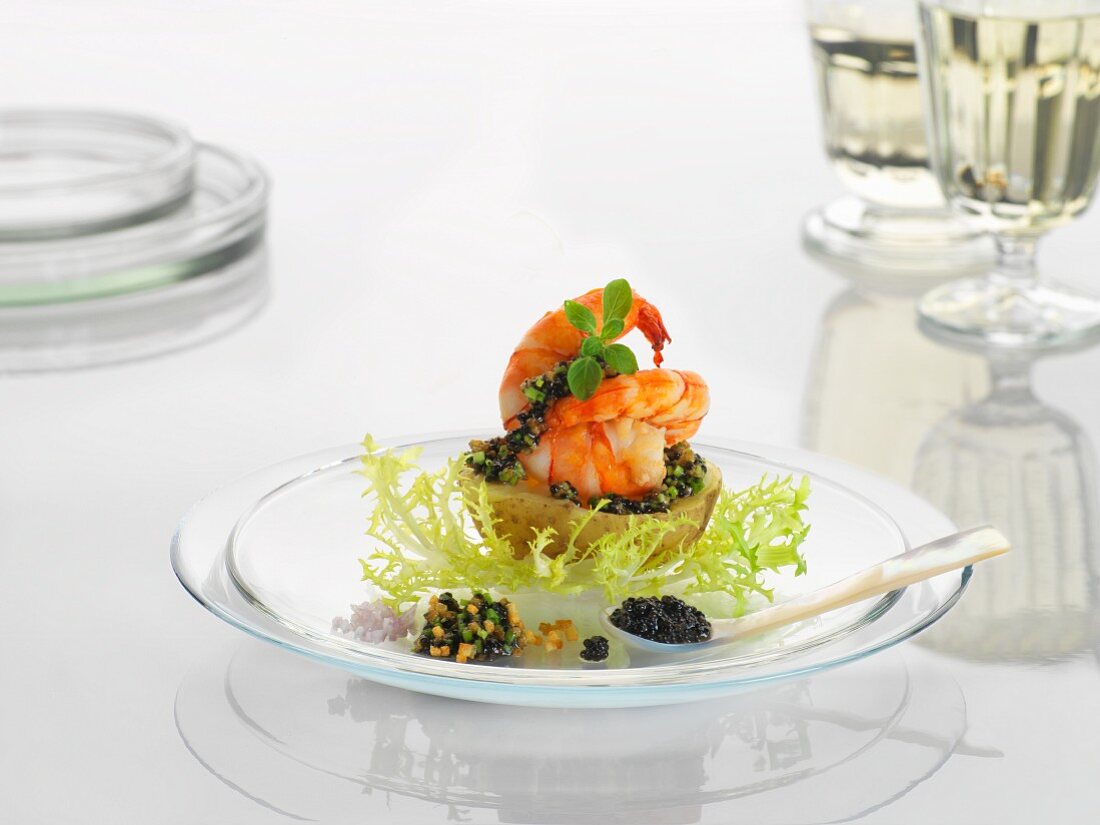 A new potato with prawns and caviar on a glass plate