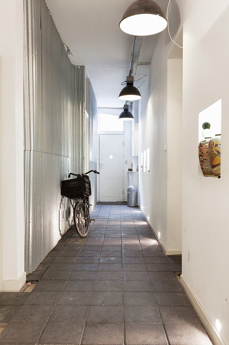 Bicycle on paved floor in narrow hallway with industrial-style pendant lamps