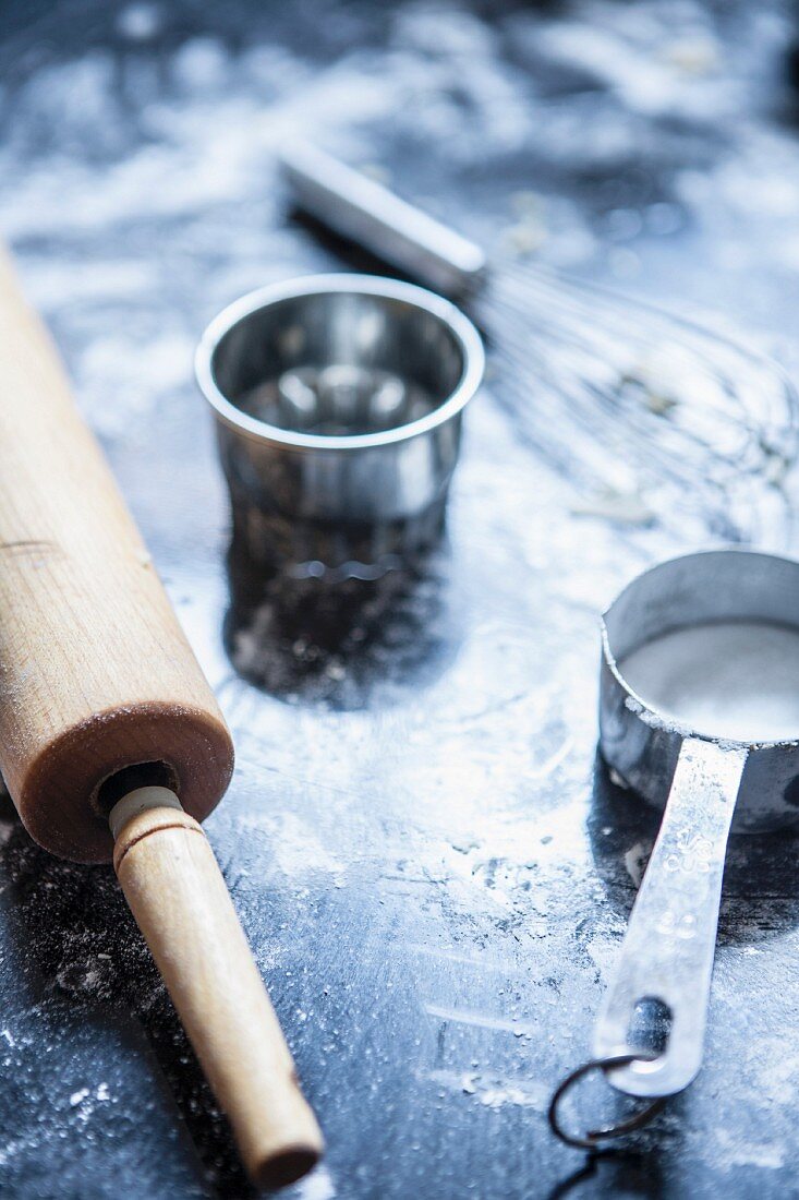 An arrangement of baking utensils with a rolling pin, a whisk and a measuring spoon