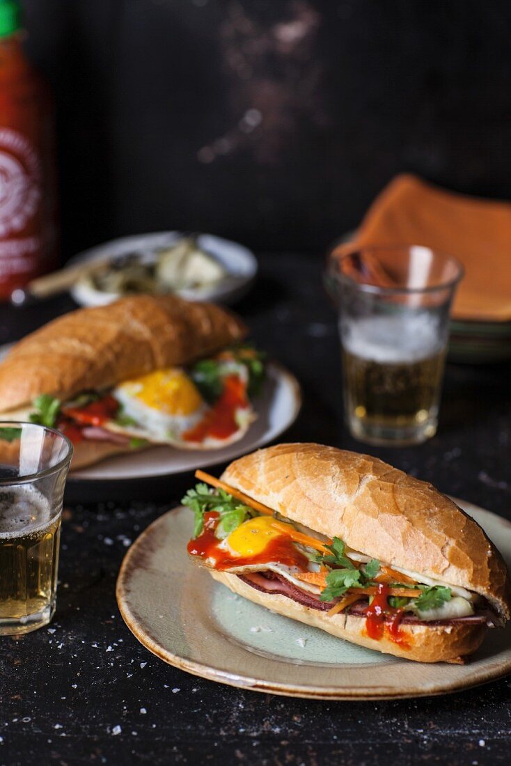 Two Bahn Mi (Vietnamese sandwiches) with ham, vegetables and fried egg