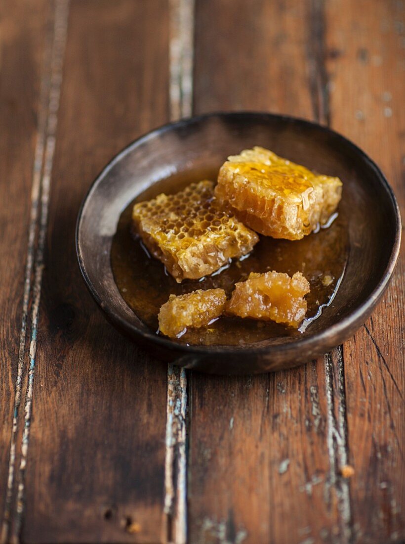 Bienenwaben mit Honig liegen in brauner Keramikschale