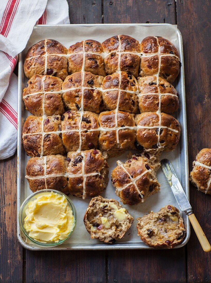 Hot cross buns on a baking tray with butter