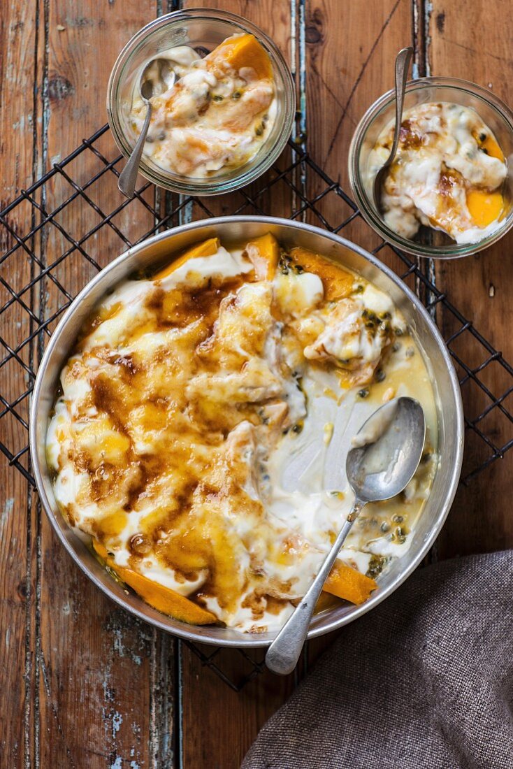 Mango, passion fruit and yoghurt gratin in a baking dish and two bowls