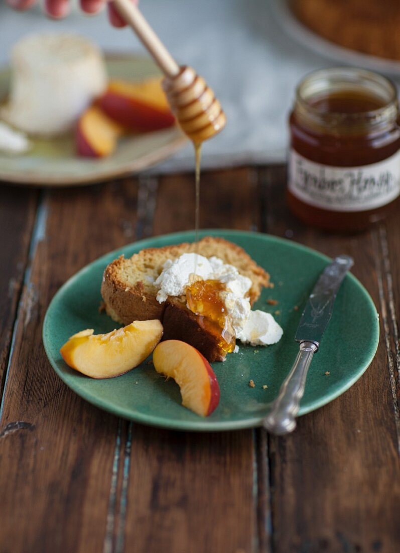 A slice of chiffon cake with olive oil served with cheese, nectarines and honey