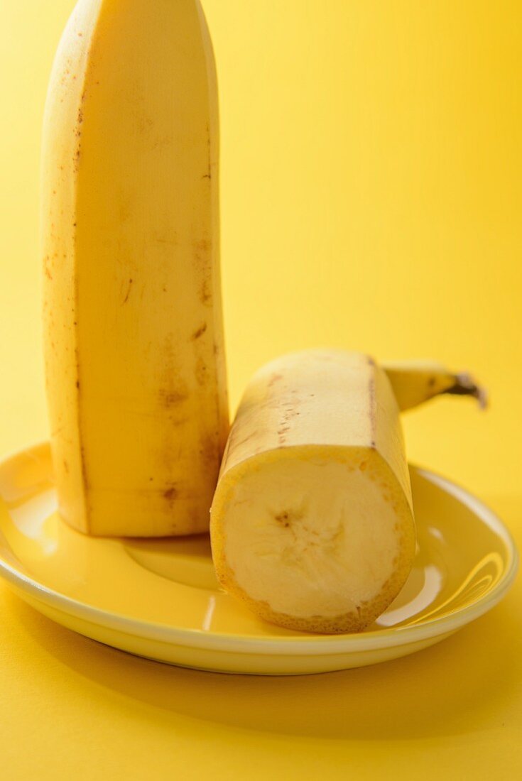 Halbierte Banane auf gelben Teller vor gelbem Hintergrund