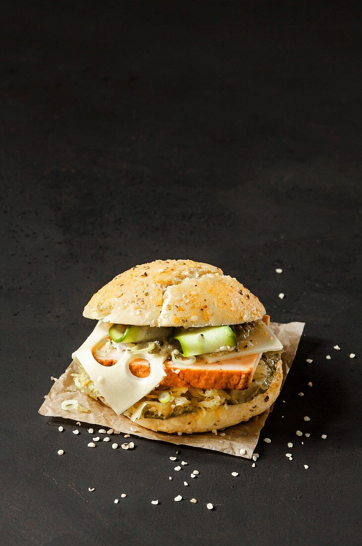 Almhütten-Burger mit Leberkäse & Kraut vor dunklem Hintergrund
