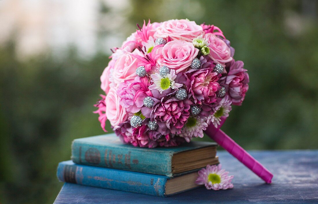 Romantic, pink bridal bouquet arranged with blue, antiquarian books
