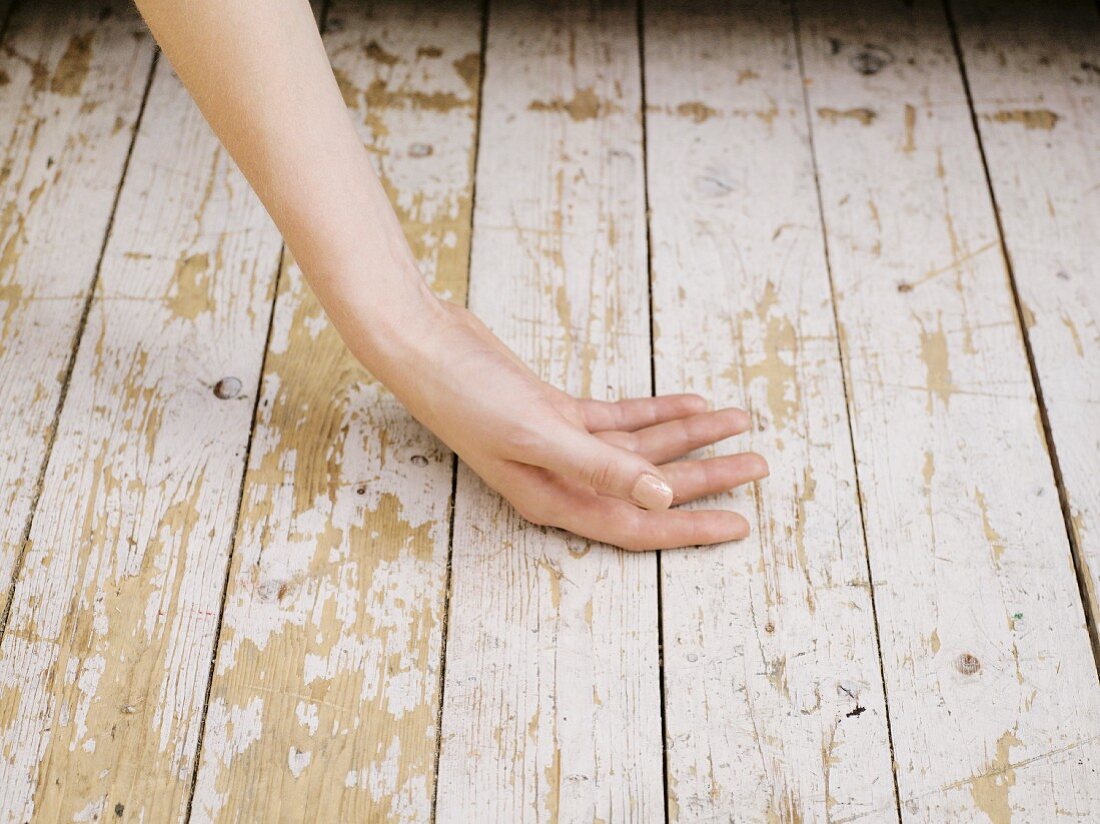 Woman's hand lying on old wooden floorboards
