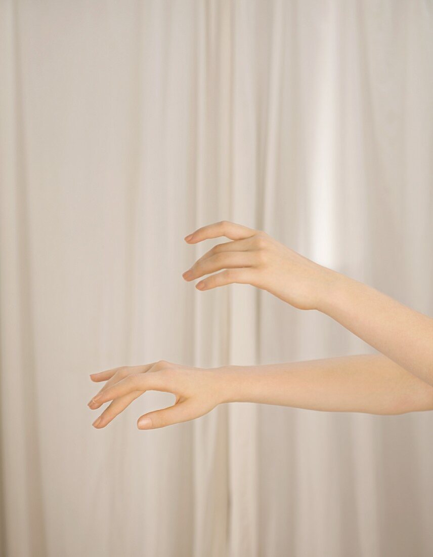Frauenhände vor weißem Vorhang