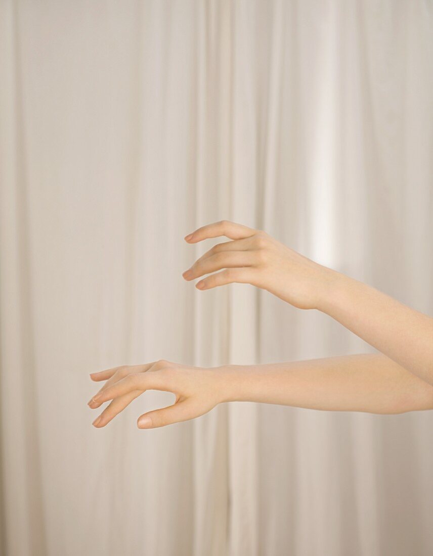 Woman's hands in front of white curtain