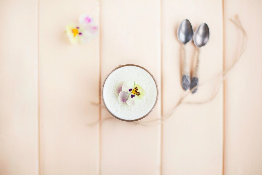 Light lemon cream with pansies on a light wooden surface