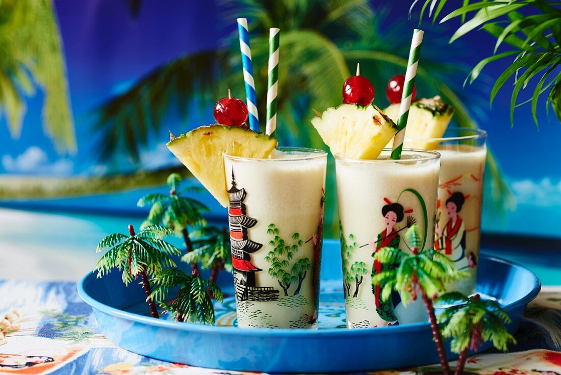Pina coladas garnished with pineapple and cocktail cherries