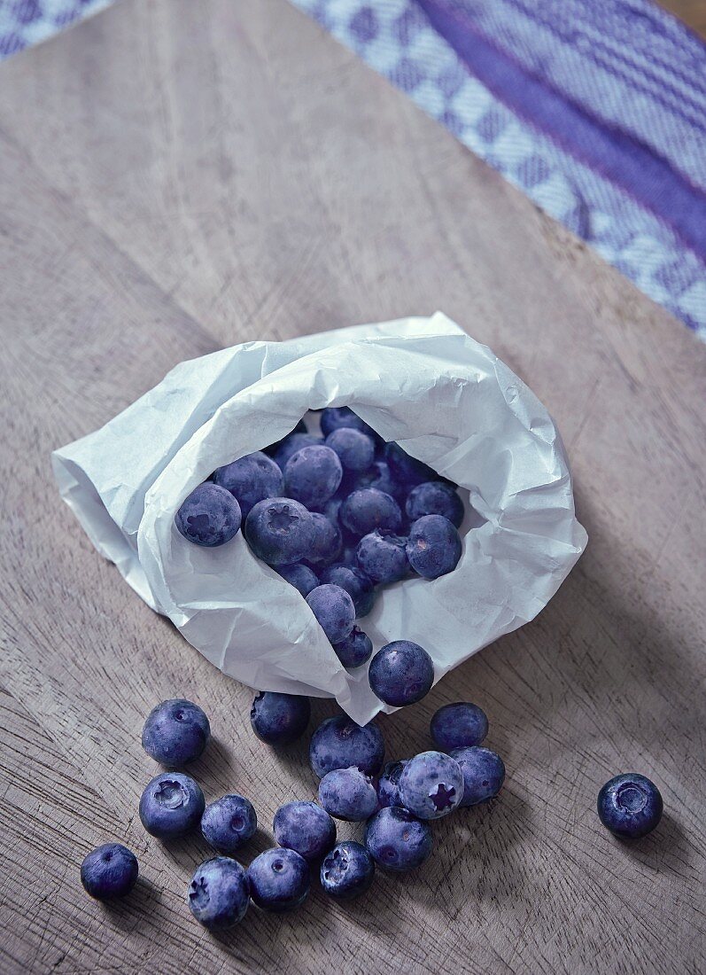 Blueberries on a wooden table with a paper bag
