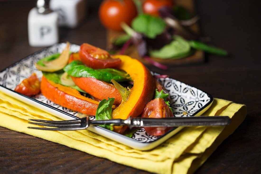 Ofengebratener Kürbis auf gemischtem Salat mit Tomaten und Zwiebeln