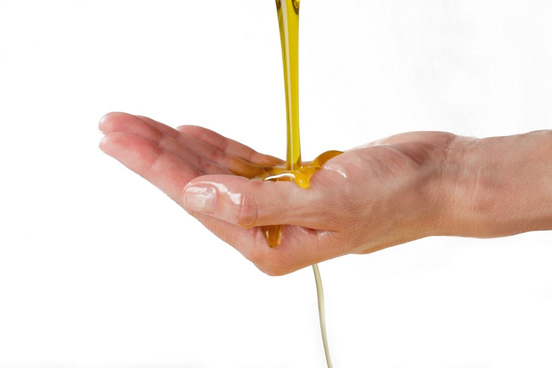 Olive oil running over woman's cupped hand