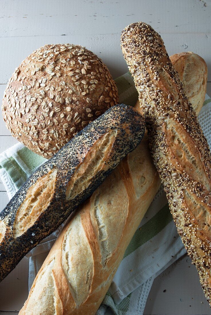 A loaf of oat bread and various baguettes