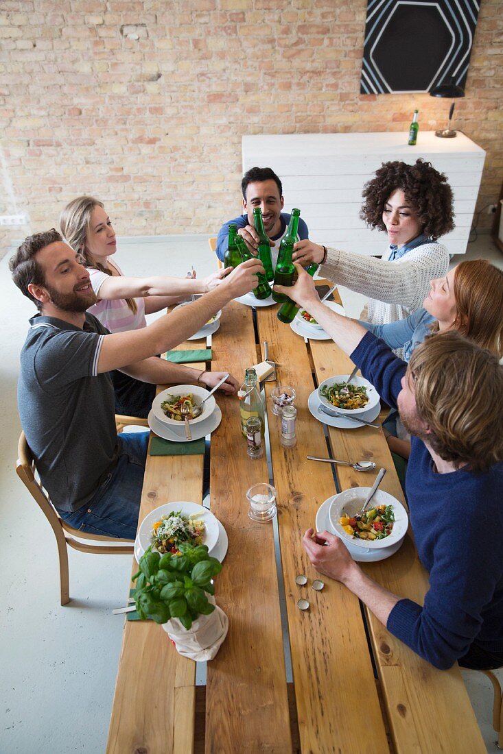 Friends eating together: raising a toast with beer bottles