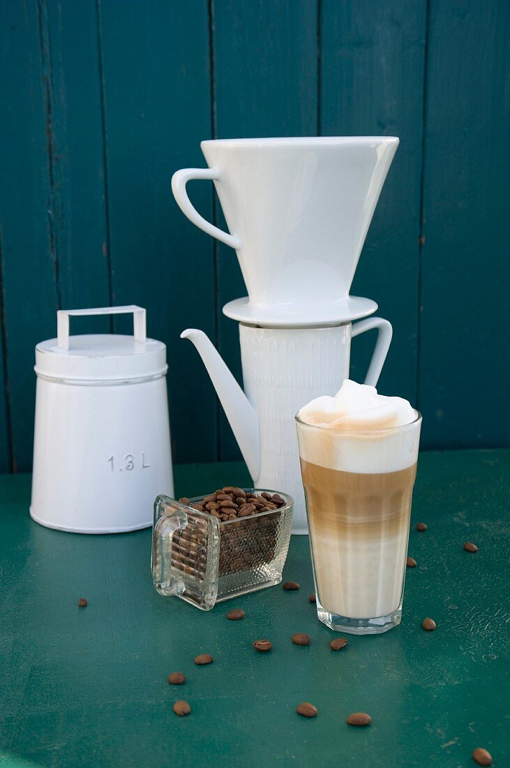 Kaffeestilleben mit Vintage-Kaffeedose, Filter, Kanne, Kaffeebohnen & Latte Macchiato