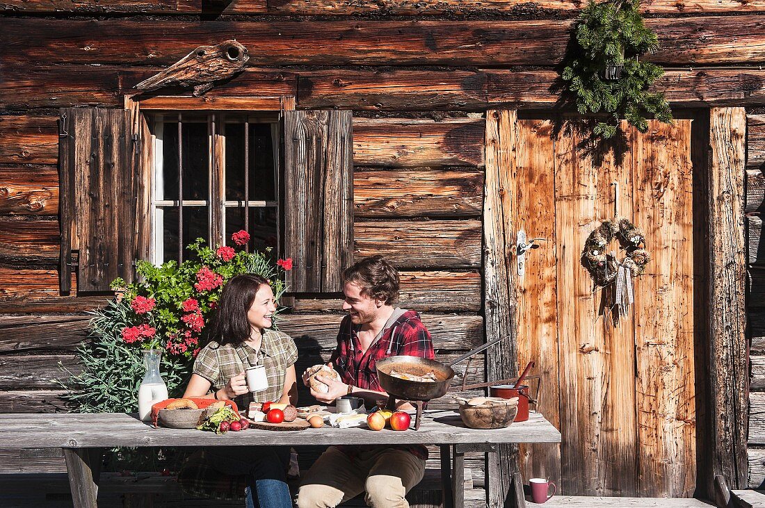 A young couple in front of an alpine hut (Altenmarkt-Zauchensee, Salzburger Land, Austria)