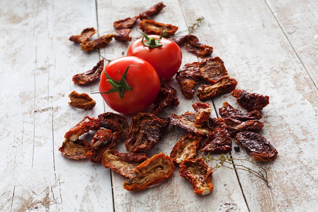 Fresh and dried tomatoes on a wooden surface
